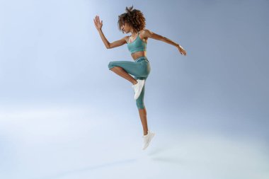 Athletic active woman jumping on studio background. Dynamic movement