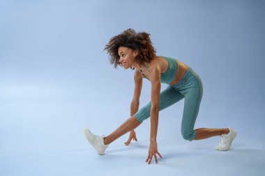 Sporty woman doing warm-up before training session in gym on studio background. High quality photo
