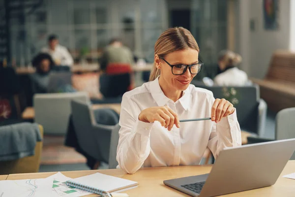 戴着眼镜的女商人坐在现代同事的工作环境中 在笔记本电脑上工作 高质量的照片 — 图库照片
