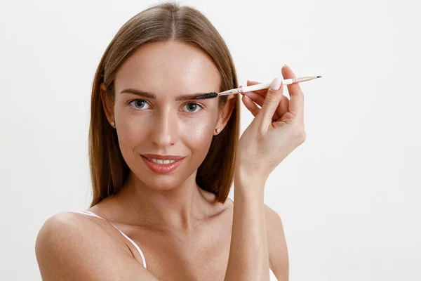 Junge Frau Kämmt Ihre Augenbrauen Mit Brauenbürste Über Weißem Studiohintergrund — Stockfoto