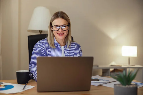 自宅のオフィスからノートパソコンで働く眼鏡の魅力的な女性のフリーランサー 高品質の写真 — ストック写真