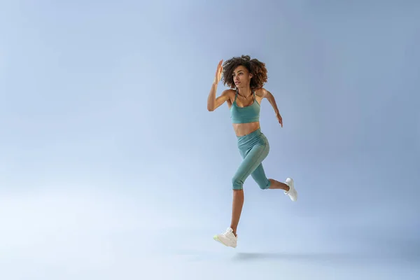 运动活跃的女人跳在工作室的背景 动态运动 — 图库照片