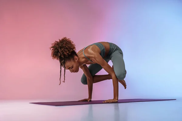 健身女人在工作室背景的垫子上练习瑜伽 用彩色滤镜 高质量的照片 — 图库照片