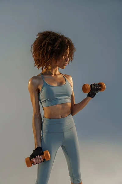 肌肉发达的女人带着体重增加的哑铃在工作室里做运动 — 图库照片