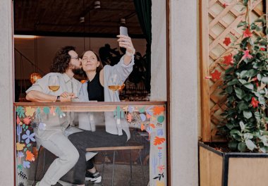 Romantik bir buluşma sırasında barda şarap içerken öpüşen ve selfie çeken bir çift. Yüksek kalite fotoğraf