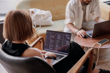 Kadın programcı, modern bir iş birliğinde otururken dizüstü bilgisayara program kodları yazar. Yüksek kalite fotoğraf
