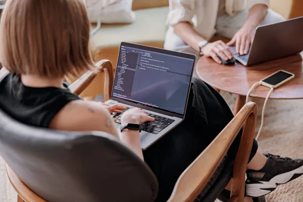 女程序员坐在现代的协同工作中 在笔记本电脑上编写程序代码 高质量的照片 — 图库照片