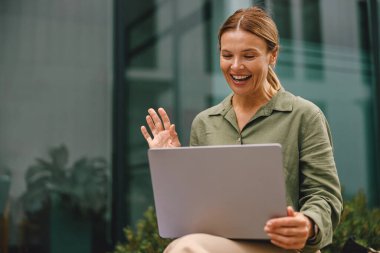 Tarz sahibi kadın müşteriyle görüntülü görüşme ve el sallama yoluyla konuşuyor.