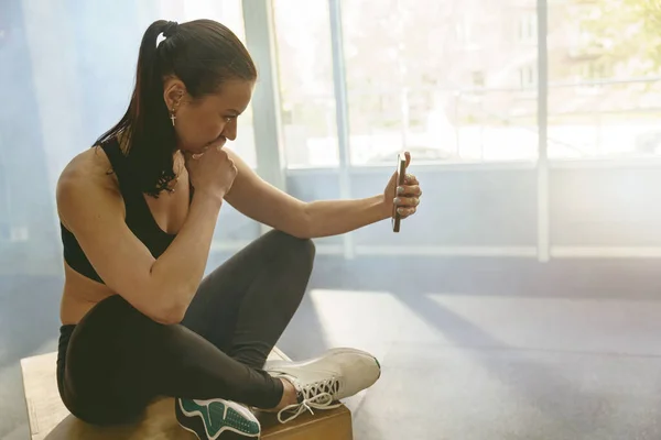 Spor Giyim Bölümündeki Sağlıklı Kadın Spor Salonunda Dinlenirken Telefon Kullanıyor — Stok fotoğraf