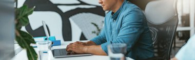 Asian businessman working on computer sitting on colleagues background. High quality photo clipart