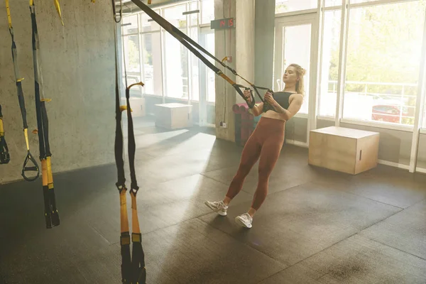 フィットネスジムセンターでTrx弾性ロープで若いフィット女性のトレーニング 高品質の写真 — ストック写真
