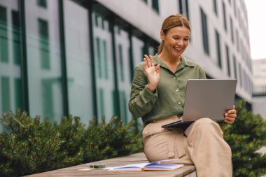 Tarz sahibi kadın müşteriyle görüntülü görüşme ve el sallama yoluyla konuşuyor.