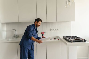 Üniformalı bir erkek işçi işe başlamadan önce ev planıyla mutfakta duruyor. Yüksek kalite fotoğraf