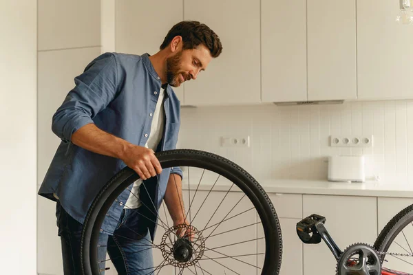 穿着休闲装的英俊男子在家里修理自行车 高质量的照片 — 图库照片