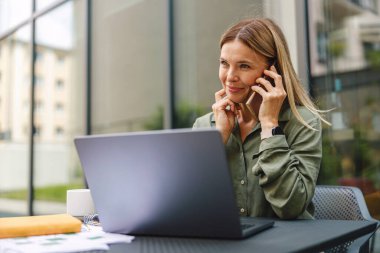 Businesswoman talking with client and work on laptop outside of office. Distance work concept