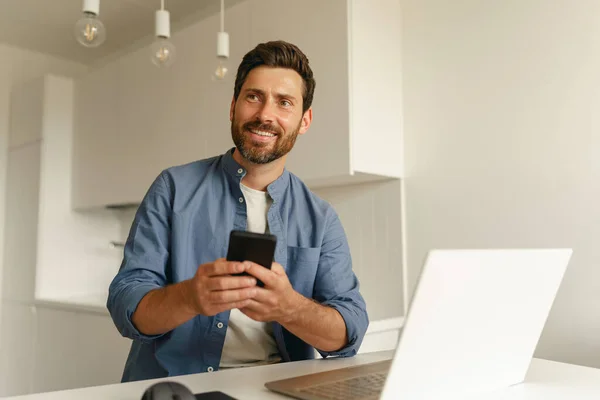 Empreendedor Masculino Segurando Telefone Enquanto Trabalhava Laptop Cozinha Doméstica Conceito — Fotografia de Stock