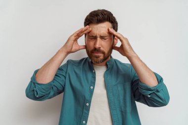 Kafaya dokunan ve beyaz arka planda acı veren baş ağrısından somurtan bir adam. Yüksek kalite fotoğraf