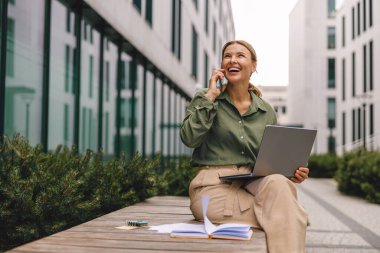 Businesswoman talking with client and work on laptop outside of office. Distance work concept