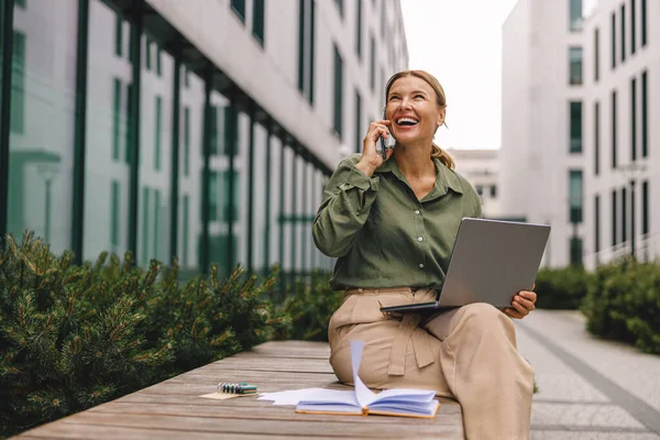 Businesswoman talking with client and work on laptop outside of office. Distance work concept