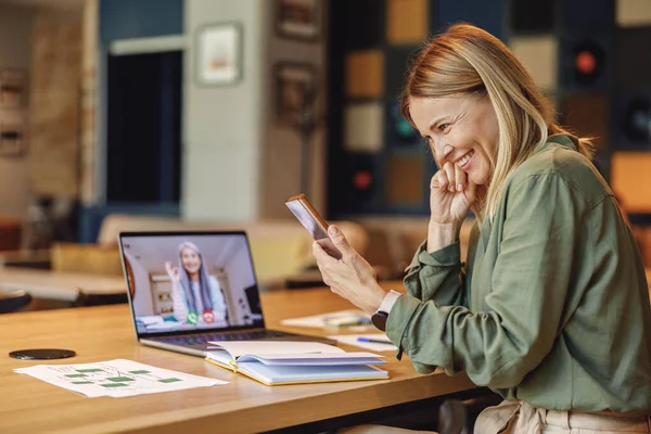 Stylish woman freelancer talking with client via video call while sitting in cafe