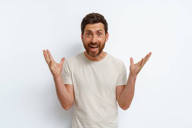 Beyaz arka planda duran şık tişörtlü bir adam ellerini açtı. Yüksek kalite fotoğraf