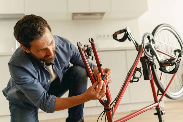 Bonito Homem Sorridente Roupas Casuais Reparando Própria Bicicleta Casa Foto — Fotografia de Stock