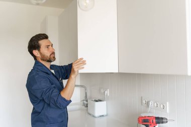 Erkek işçi mutfak dolabının kapısını tamir ediyor. Ev yenileme konsepti