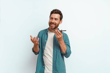 Beyaz arka planda dururken telefonda sesli mesaj kaydeden yakışıklı bir adam. Yüksek kalite fotoğraf