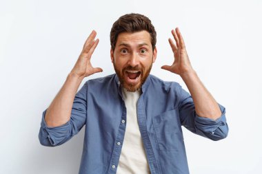 Beyaz arka planda duran ve kollarını kaldırıp bağıran şok olmuş bir adam. Yüksek kalite fotoğraf