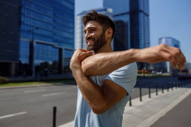 Sağlıklı sporcu adam modern şehir gökdelenlerinin arka planında geriniyor. Yüksek kalite fotoğraf