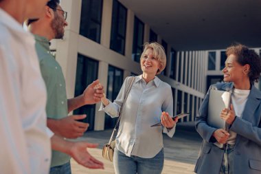 Profesyonel iş ekibi, modern ofis binasının arka planında mola sırasında görüştü