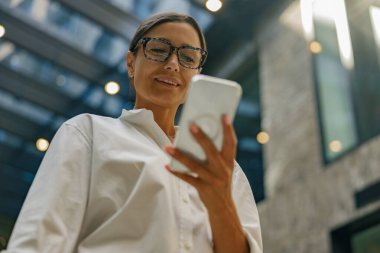 Gülümseyen kadın satış müdürü birlikte çalışırken cep telefonuna bakıyor.