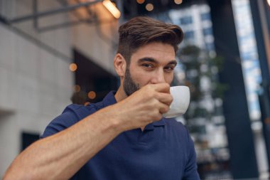 Modern çalışma geçmişinde kahve içen yakışıklı sakallı adamı yakından çek. Yüksek kalite fotoğraf