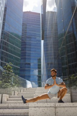Sağlıklı sporcu adam modern şehir gökdelenlerinin arka planında geriniyor. Yüksek kalite fotoğraf