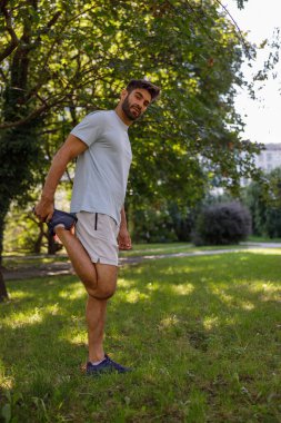 Spor giyimli yakışıklı adam şehir parkında koşmadan önce ısınıyor. Yüksek kalite fotoğraf
