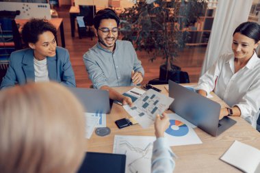 Ofiste belgelerle çalışan ve dizüstü bilgisayar kullanan bir grup profesyonel işletme yöneticisi