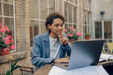 Modern ofis terasında dizüstü bilgisayarda çalışan odaklanmış kadın satış müdürü 