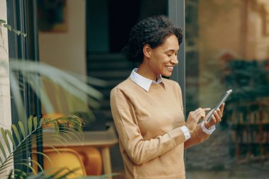 Terasta dikilen ve internetten alışveriş yapmak için cep telefonu kullanan ya da sosyal medyadan keyif alan bir kadın