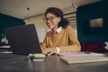 Evde otururken uzaktan bilgisayarla çalışan serbest çalışan bir kadın. Mesafe çalışma kavramı