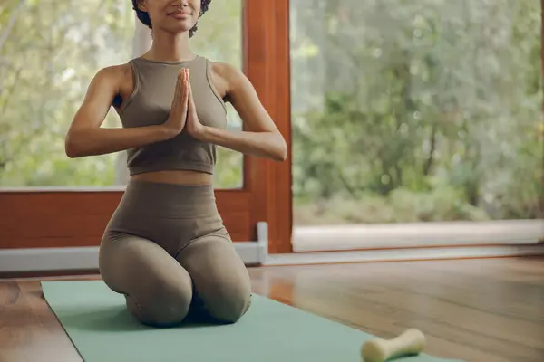 Close up of fitness woman meditate while doing yoga indoors at home on mat