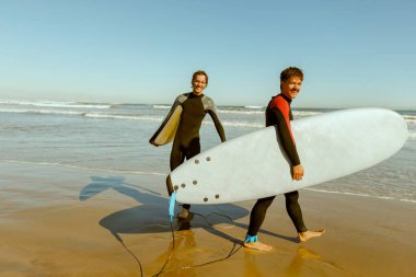 Sörf tahtası olan bir grup arkadaş dalgalar üzerinde sörf yapmak için okyanusa giriyorlar. Yüksek kalite fotoğraf 