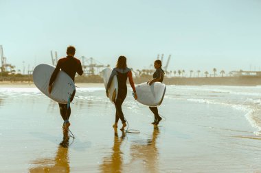 Sörf tahtası olan bir grup arkadaş dalgalar üzerinde sörf yapmak için okyanusa giriyorlar. Yüksek kalite fotoğraf 