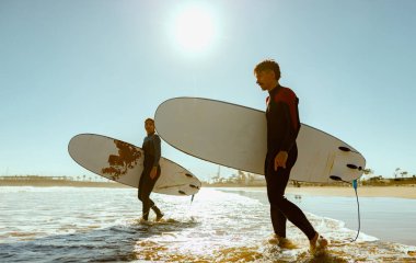 Sörf tahtası olan bir grup arkadaş dalgalar üzerinde sörf yapmak için okyanusa giriyorlar. Yüksek kalite fotoğraf 