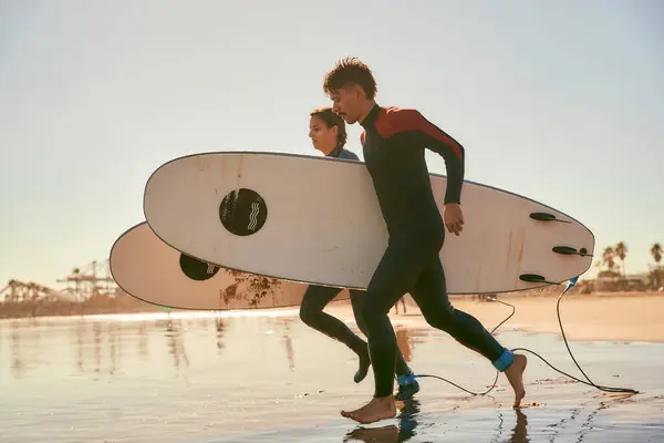Grupa Szczęśliwych Surferów Kombinezonach Wbiegających Morza Trzymających Deski Surfingowe — Zdjęcie stockowe