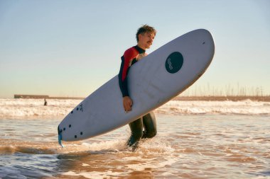 Dalgıç kıyafetli, sörf tahtası denize giren bir erkek sörfçü. Okyanusta sörf yapmak. Yüksek kalite fotoğraf