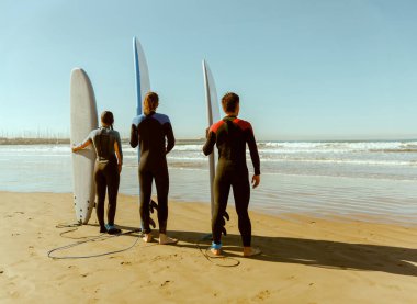 Dalgıç kıyafetli sörfçüler sörf tahtasıyla dalgalara binmeye hazırlanıyorlar. Yüksek kalite fotoğraf