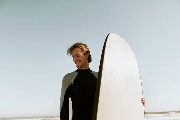Surfer in wetsuits standing with surfboard and preparing for ride on waves. High quality photo