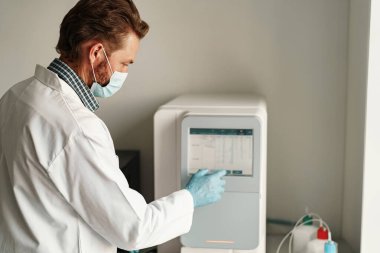 Tıbbi araştırma laboratuvarında çalışan üniformalı ve maskeli bir erkek bilim adamı. Yüksek kalite fotoğraf