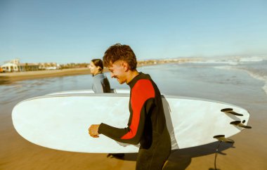 Sörf tahtası olan bir grup arkadaş dalgalar üzerinde sörf yapmak için okyanusa giriyorlar. Yüksek kalite fotoğraf 