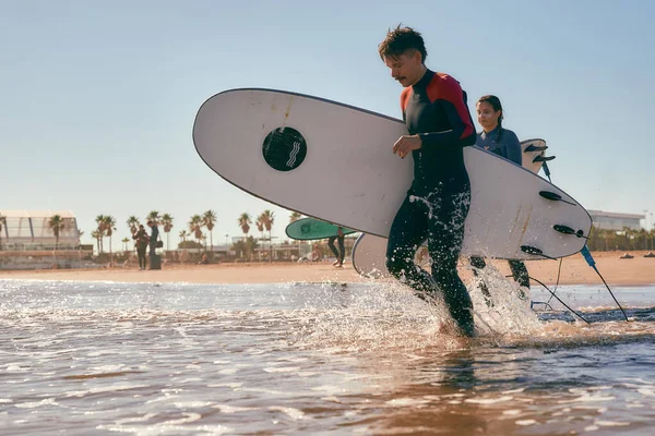 Widok Boczny Surferów Wbiegających Morza Trzymających Deski Surfingowe Wysokiej Jakości — Zdjęcie stockowe